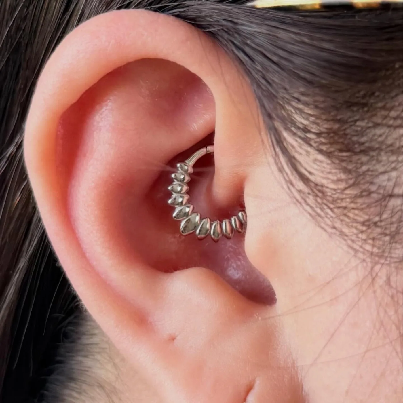 Daith piercing with a silver hinged ring lined with marquise beads