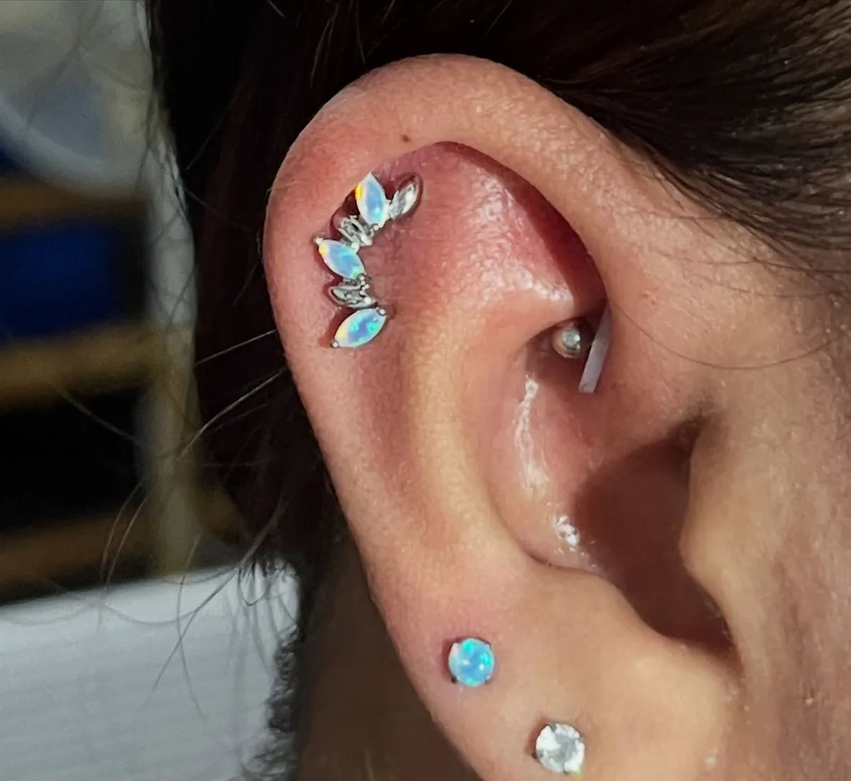 White opal marquise climber on upper cartilage with a tragus stud and opal lobe studs