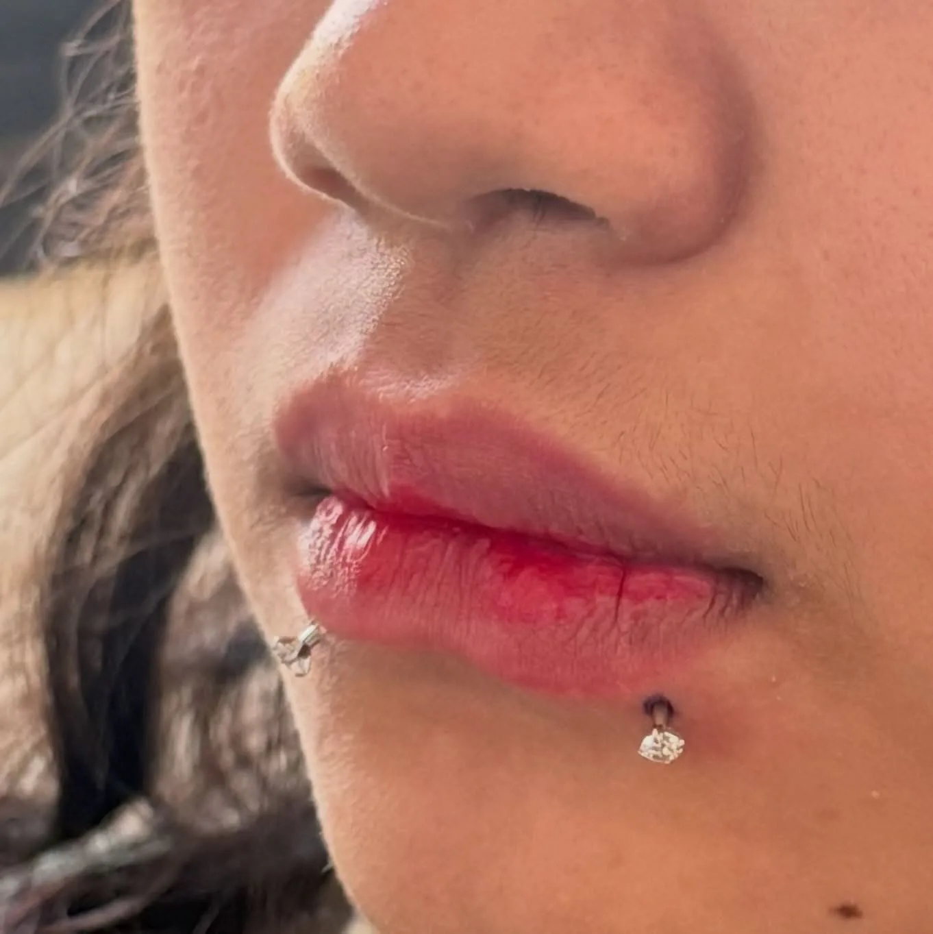 Paired lower lip piercings with silver prong-set crystal studs