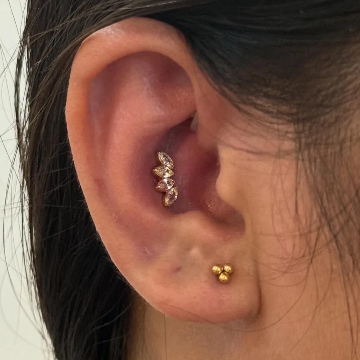 Marquise crystal fan stud on the antihelix with a gold trinity bead stud on the tragus