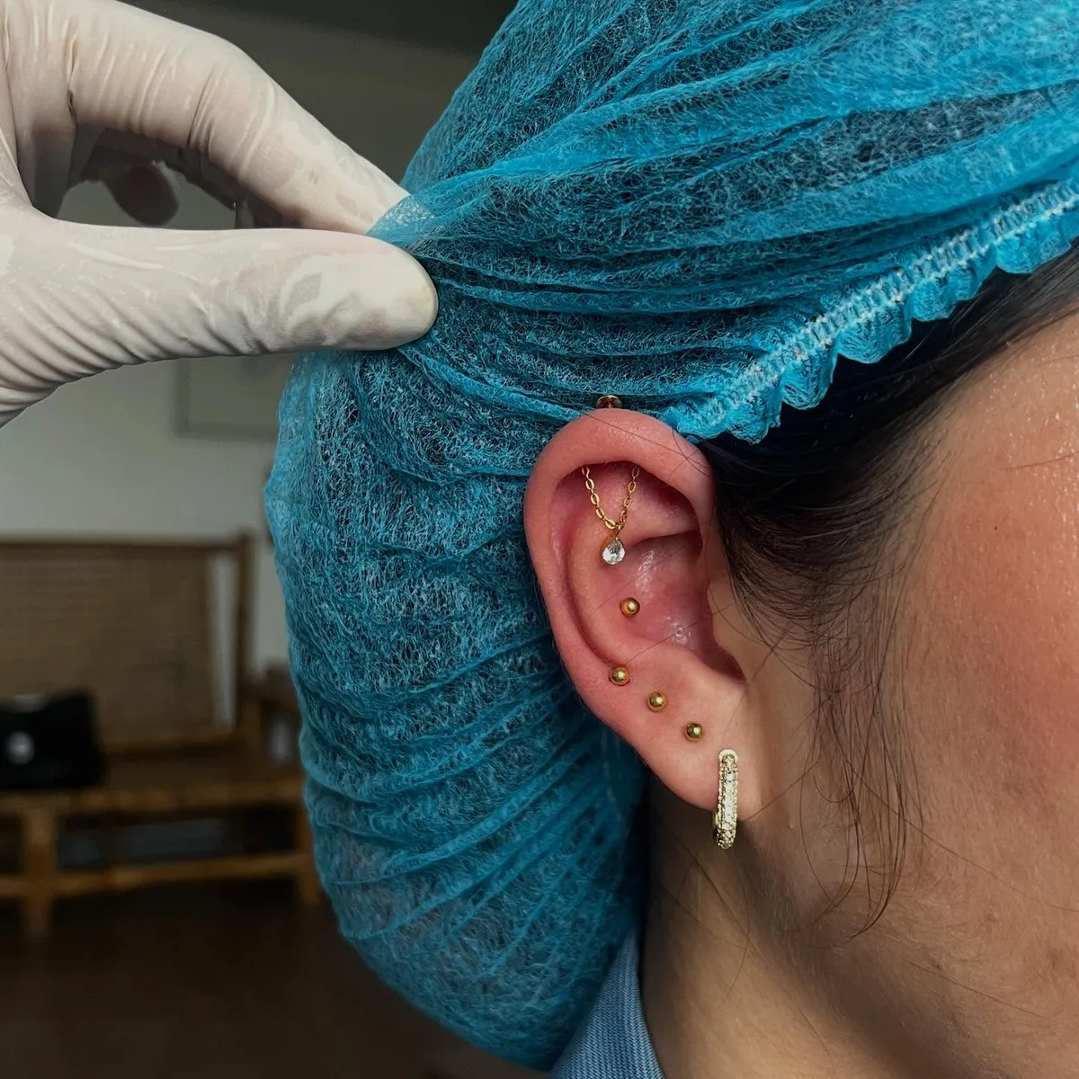 Gold curated ear stack with a chain-drop crystal, bead studs, and pave huggie hoop during a studio session