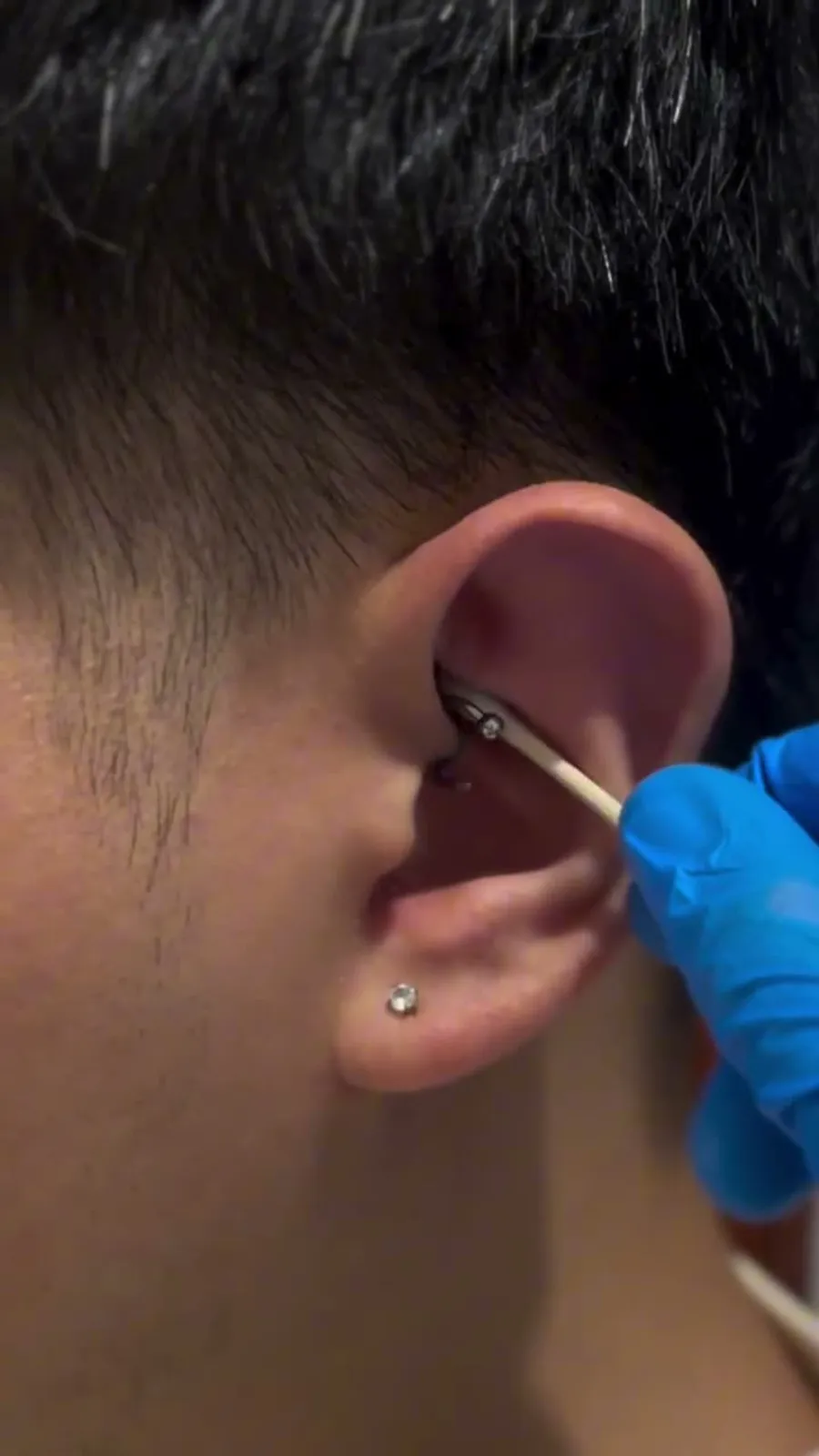Fresh rook piercing with a silver curved barbell, with a small gem stud on the earlobe